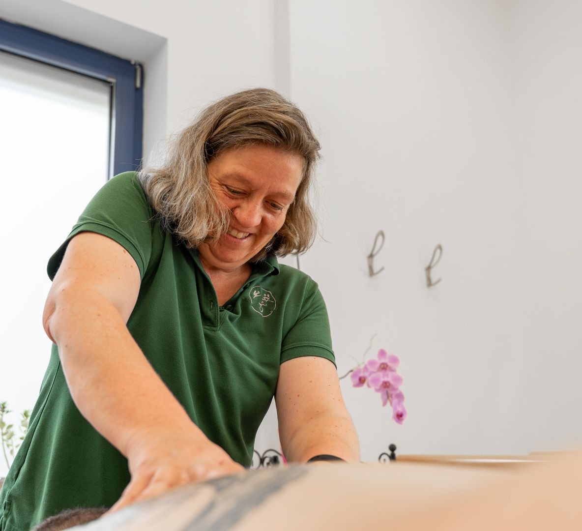 Eine Mitarbeiterin massiert einen Patienten.